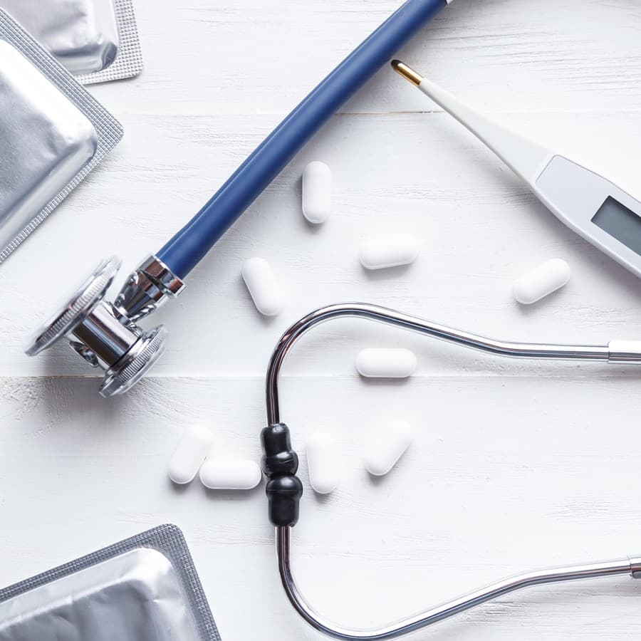 Antibiotics concept. Stethoscope with flu antibiotic and thermometer on white table

