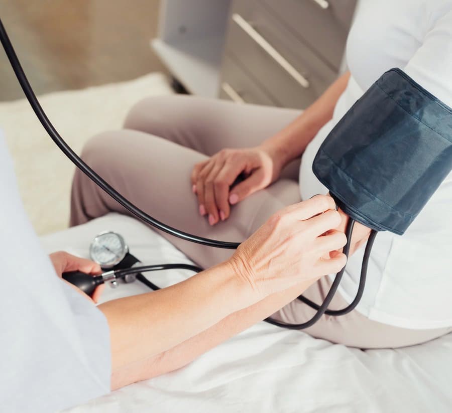 Close-up partial view of nurse measuring blood pressure to senior patient

