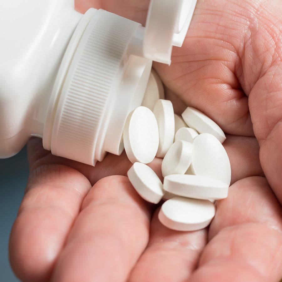 calcium dietary supplements in the palm of a woman's hand
