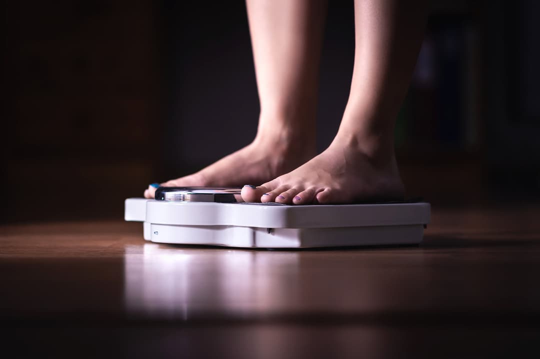 Feet on scale. Weight loss and diet concept. Woman weighing herself. Fitness lady dieting. Weightloss and dietetics. Dark late night mood.
