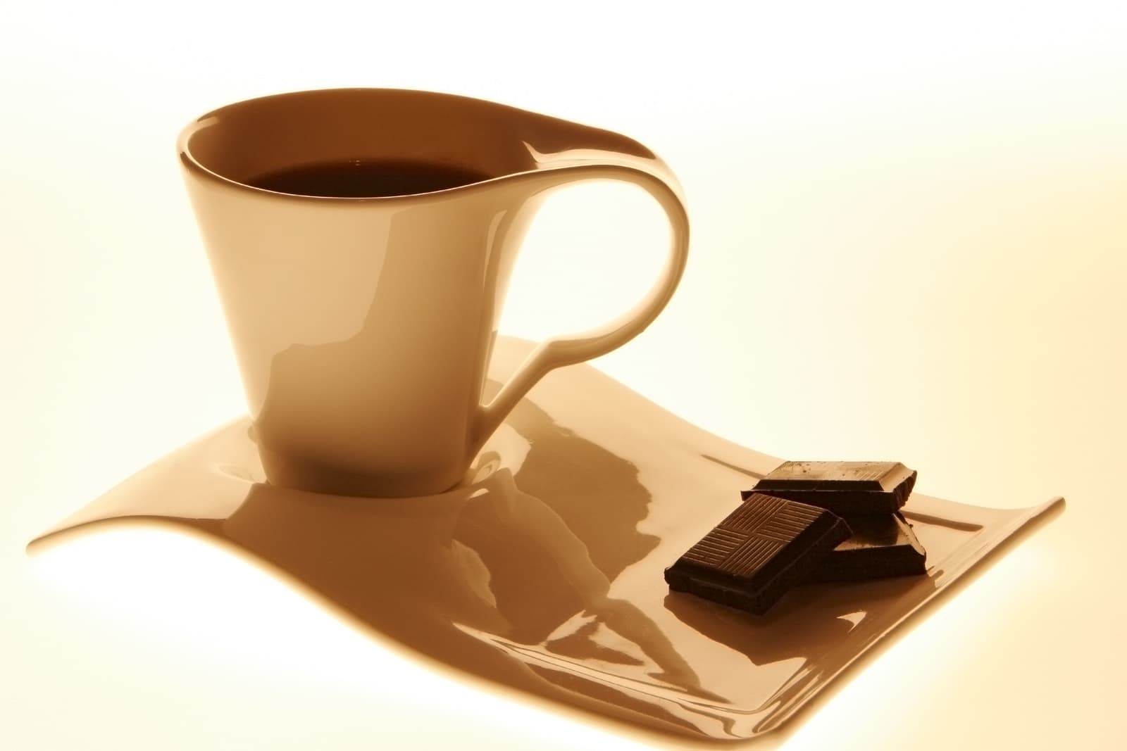 Cup of black coffee and two squares of dark chocolate on a tray