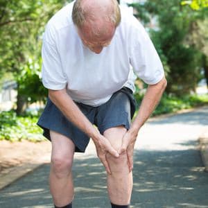 a man with arthritic knees, holding his knee in pain