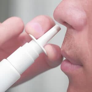 Man uses a nasal spray for treatment