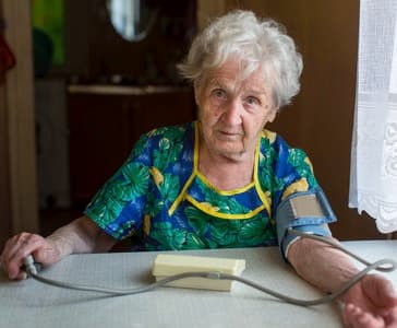 Elderly woman pensioner measures the blood pressure itself.
