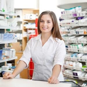 Portrait of female pharmacist standing at counter in pharmacy