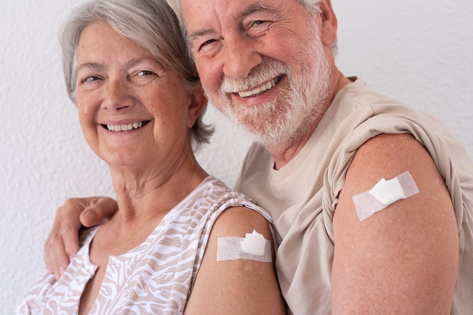 Smiling seniors showing off vaccinations