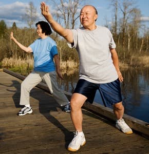 two seniors practice tai qi (tai chi) outdoors
