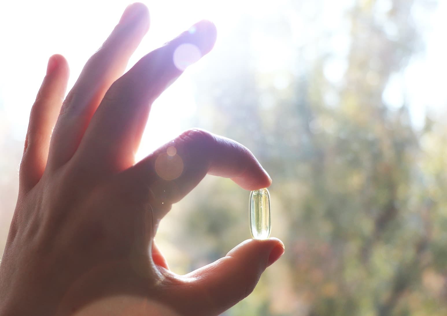 hand holds high dose vitamin D capsule between thumb and forefinger