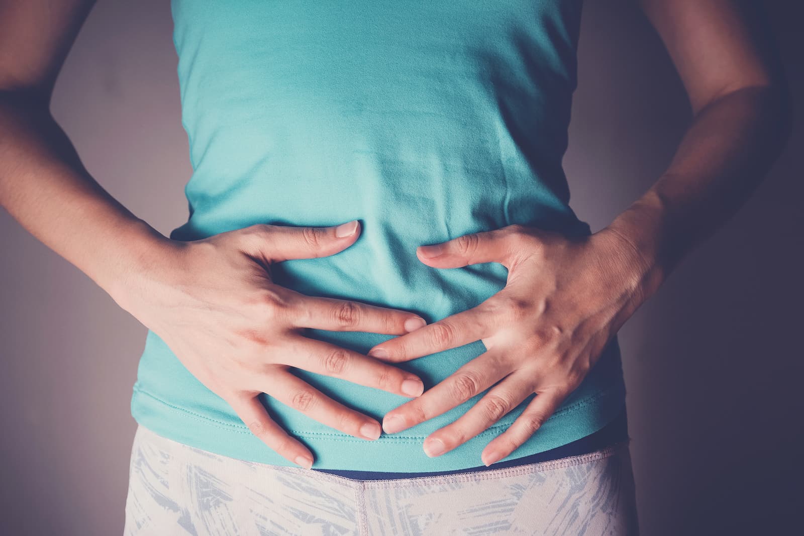 woman has hands on her abdomen for symptoms of IBS
