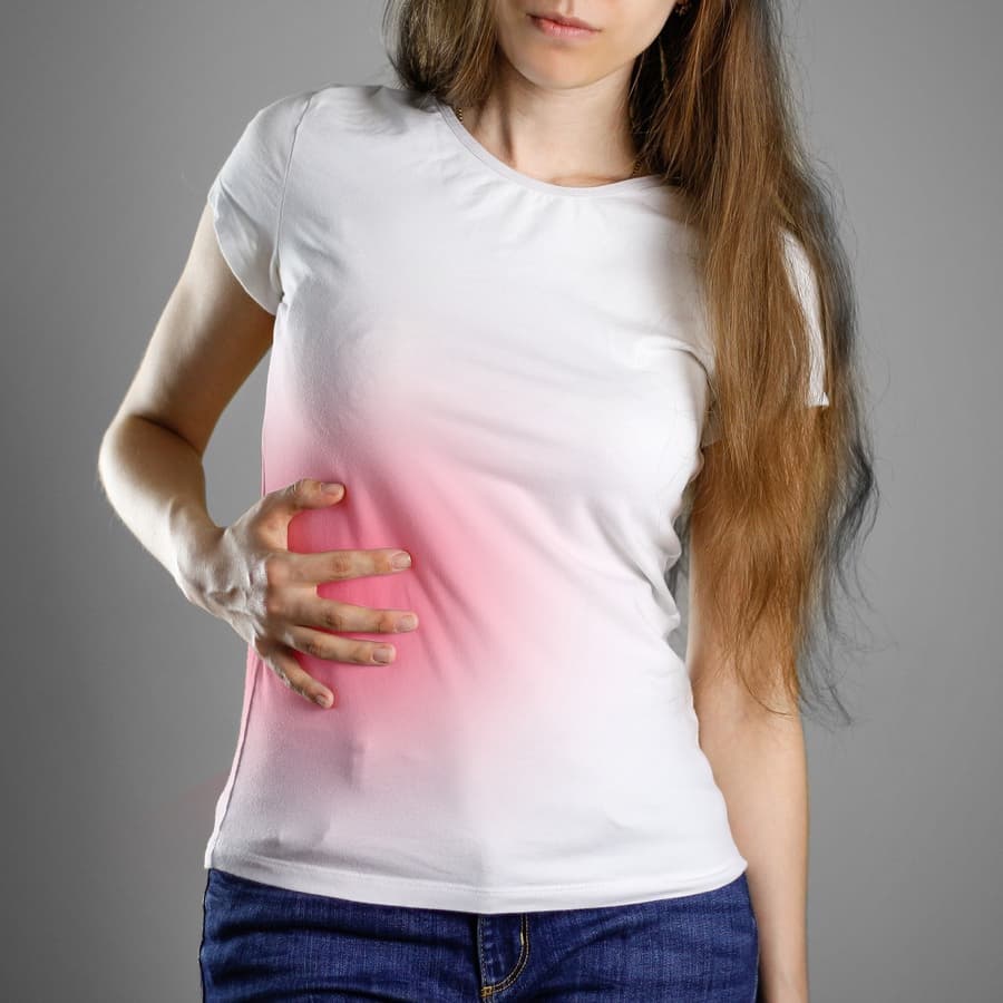 Woman holds her side suffering from acute liver injury pain or liver cancer