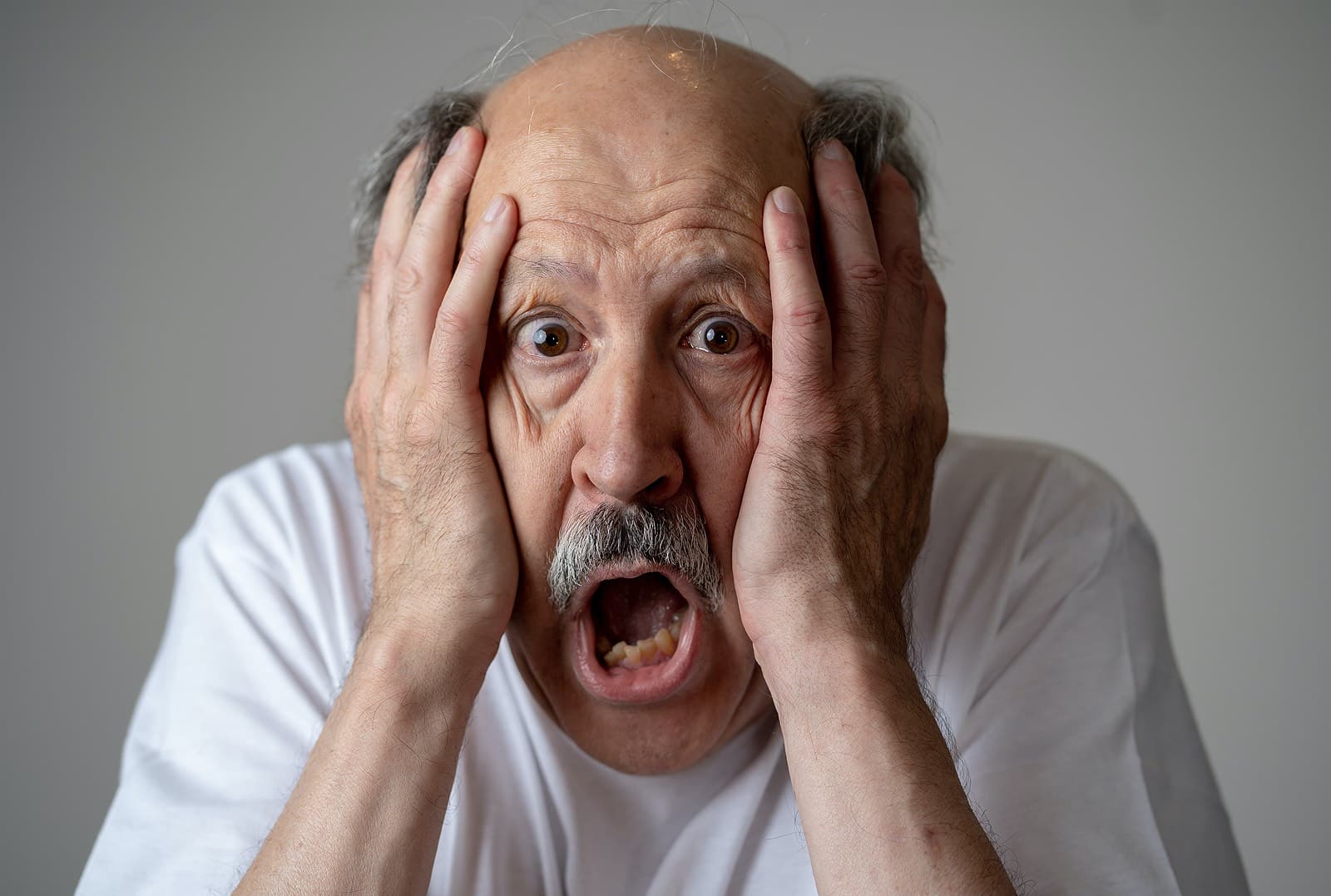 A disoriented man with memory problems and dementia holding his face is dismay