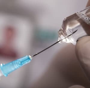 a hypodermic needle inserted into a vial of medicine