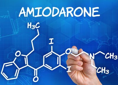 Hand with pen drawing the chemical formula of Amiodarone
