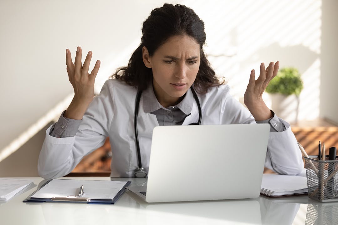 Angry female doctor have problems working on computer
