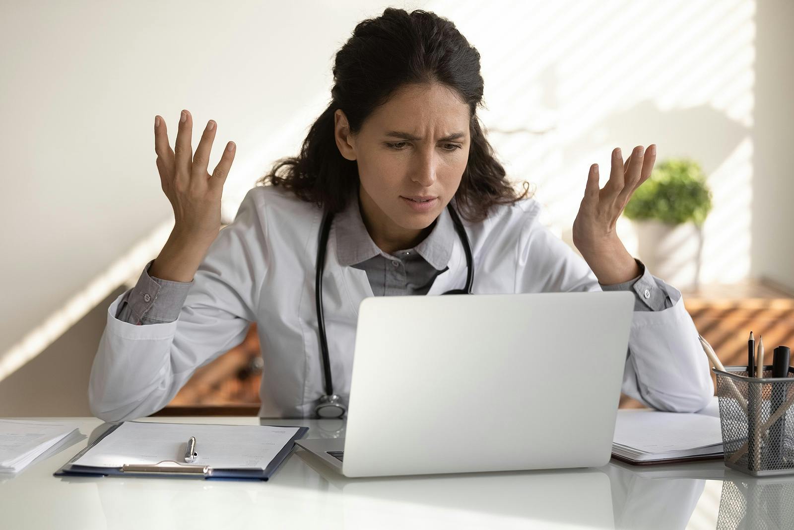 angry female doctor looking at prescription drug ad on her laptop