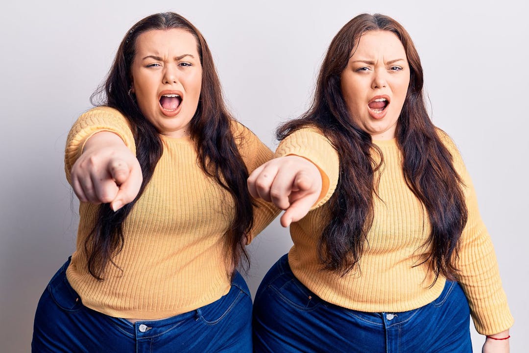 Young plus size twins wearing casual clothes pointing displeased and frustrated to the camera, angry and furious with you
