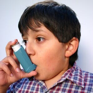 young boy with asthma using an inhaler
