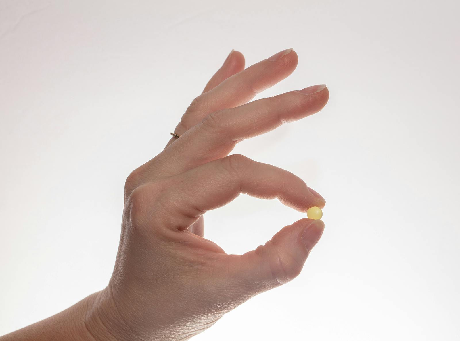 Hand holding up a single baby aspirin
