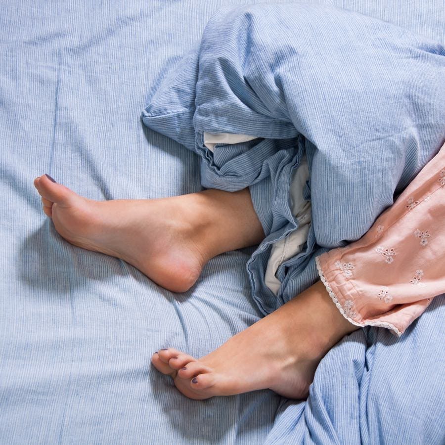Close up Bare Feet of a Young Woman Lying Down on a Blue Bed Captured in High Angle View.
