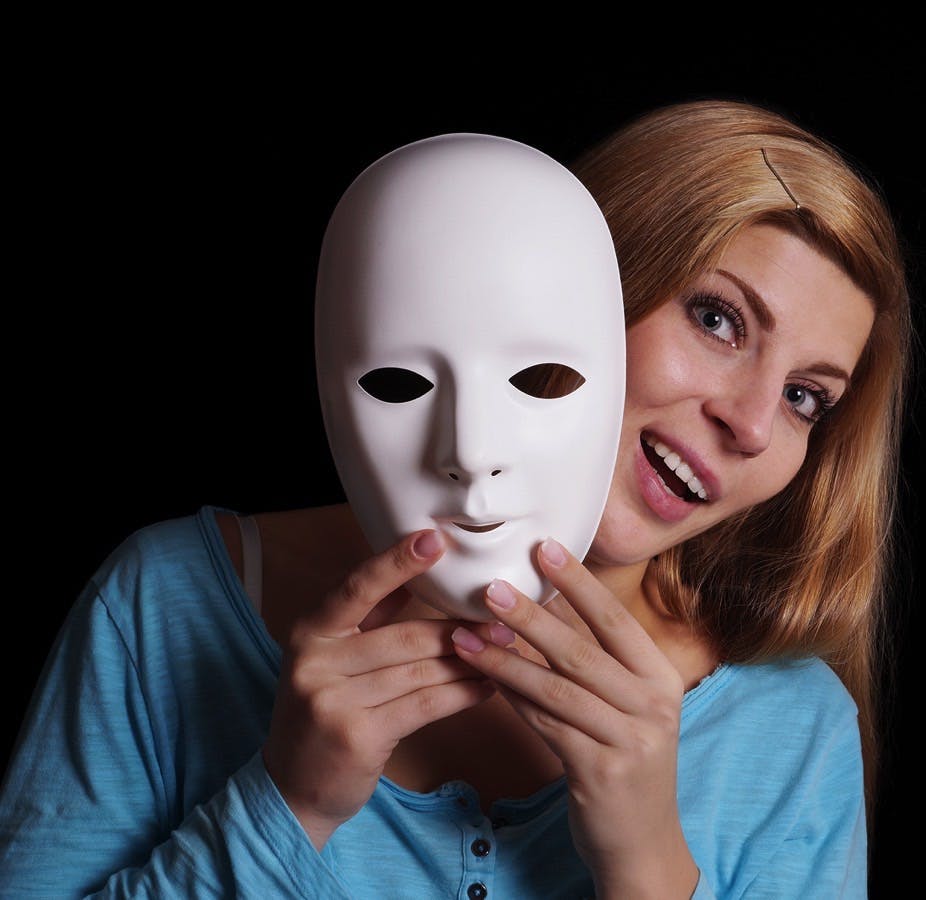 Young woman removing plain white mask from her face
