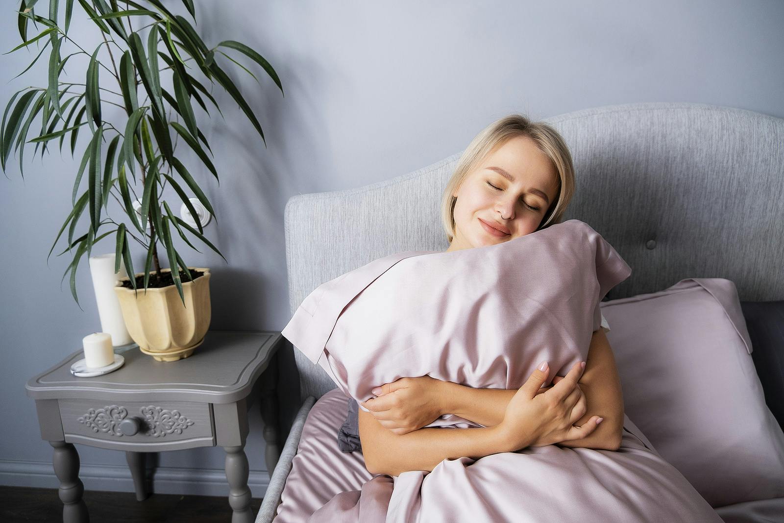 Woman hugs a pillow in bed. Do you love your pillow this much? She will be sleeping a little longer.