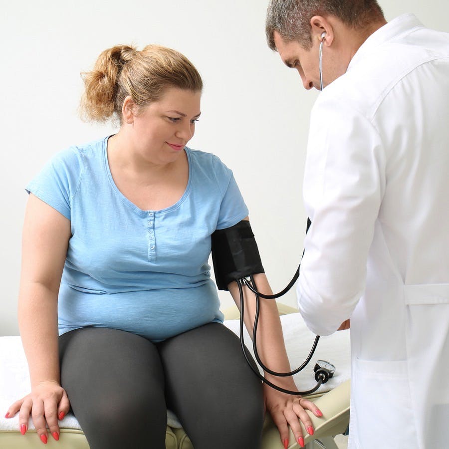 Doctor measuring blood pressure of overweight woman in hospital
