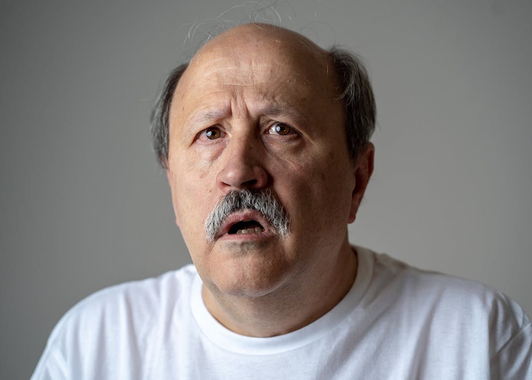 Close up portrait of senior man looking confused and lost suffering from dementia, memory loss or Alzheimer in Mental health in Older Adults and later life concept isolated on grey background.
