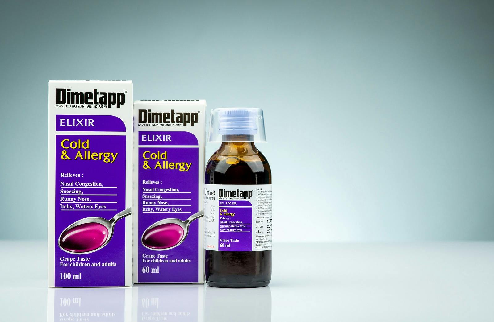 Dimetapp Elixir in amber bottle with measuring cup and packaging isolated on gradient background. Nasal decongestant and antihistamine drug. Medicine for cold.
