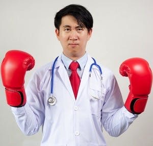 Asian Doctor wearing boxing gloves in white background
