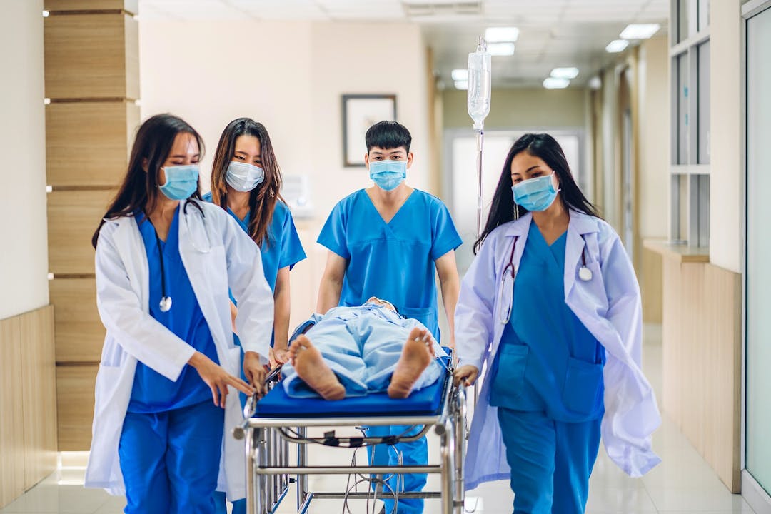 Group of professional medical doctor team and assistant with stethoscope in uniform taking seriously injured patient to operation emergency theatre room in hospital.health medical care concept
