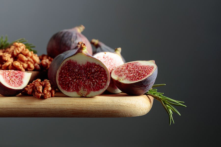 Figs, walnuts, and rosemary on a wooden table. Copy space.
