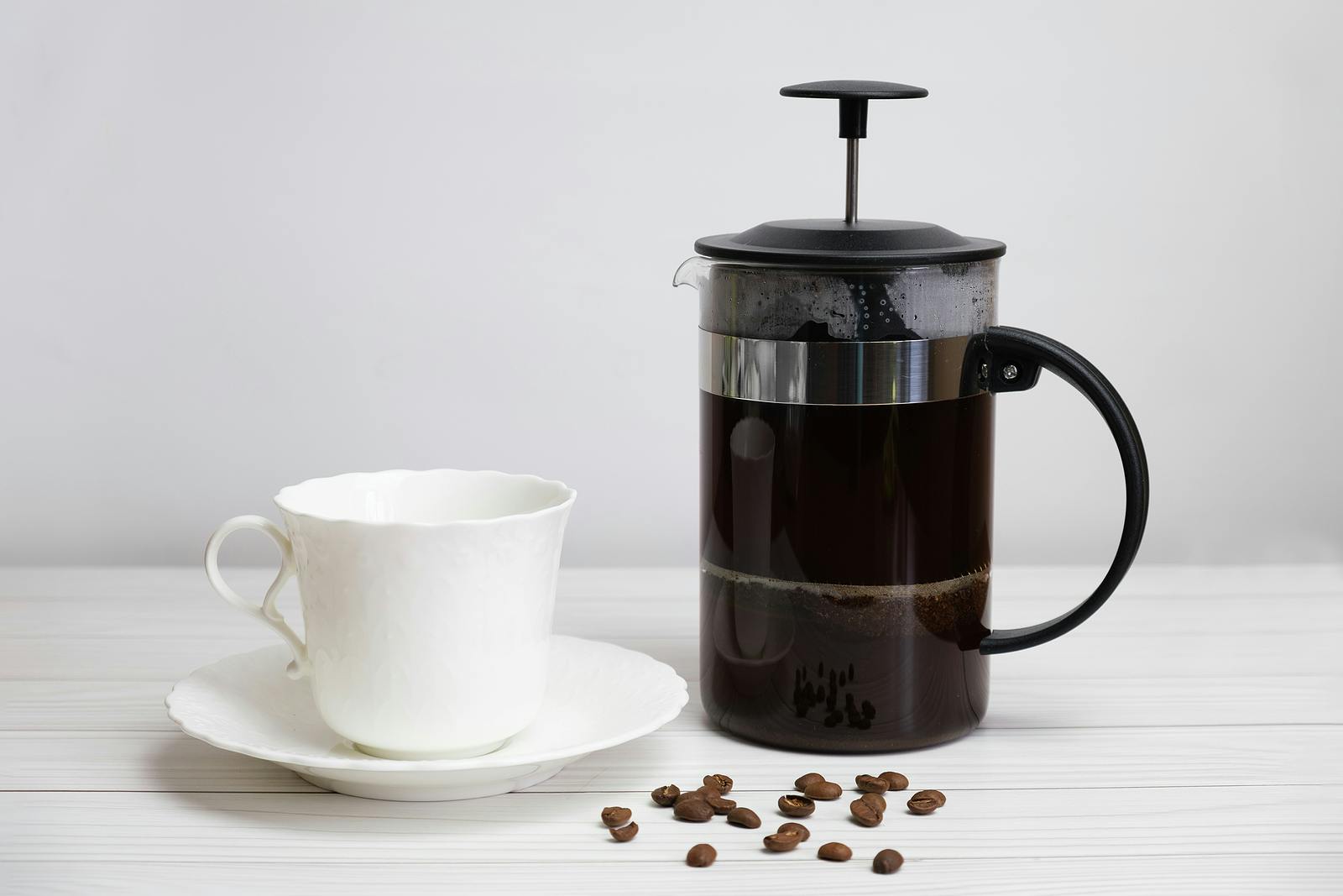 cup and saucer, coffee beans and French press for preparing unfiltered coffee
