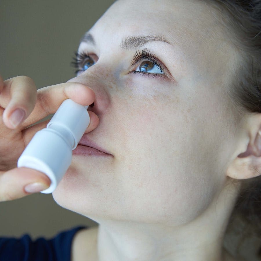 Girl sprays the spray from runny nose into the nasal pass
