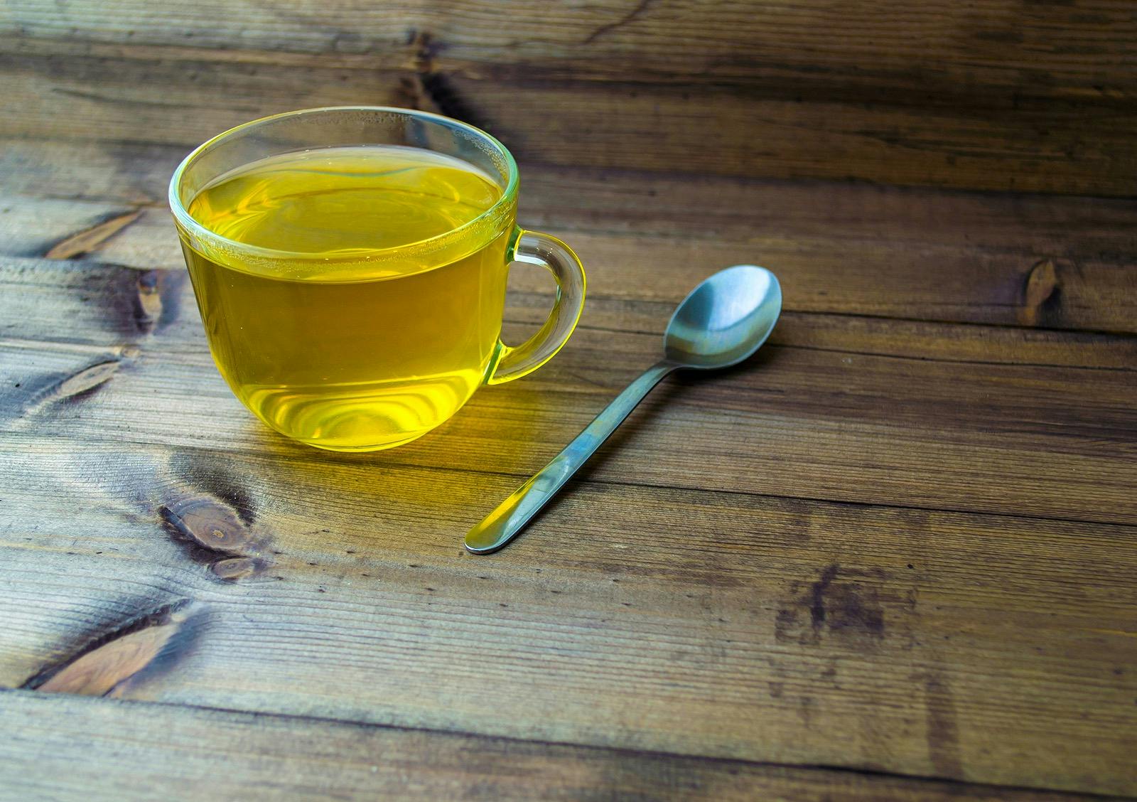 Green tea and spoon. Green tea and a spoon on a wooden table.
