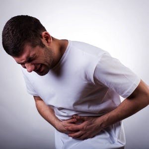 Man doubled over with heartburn pain holds his stomach
