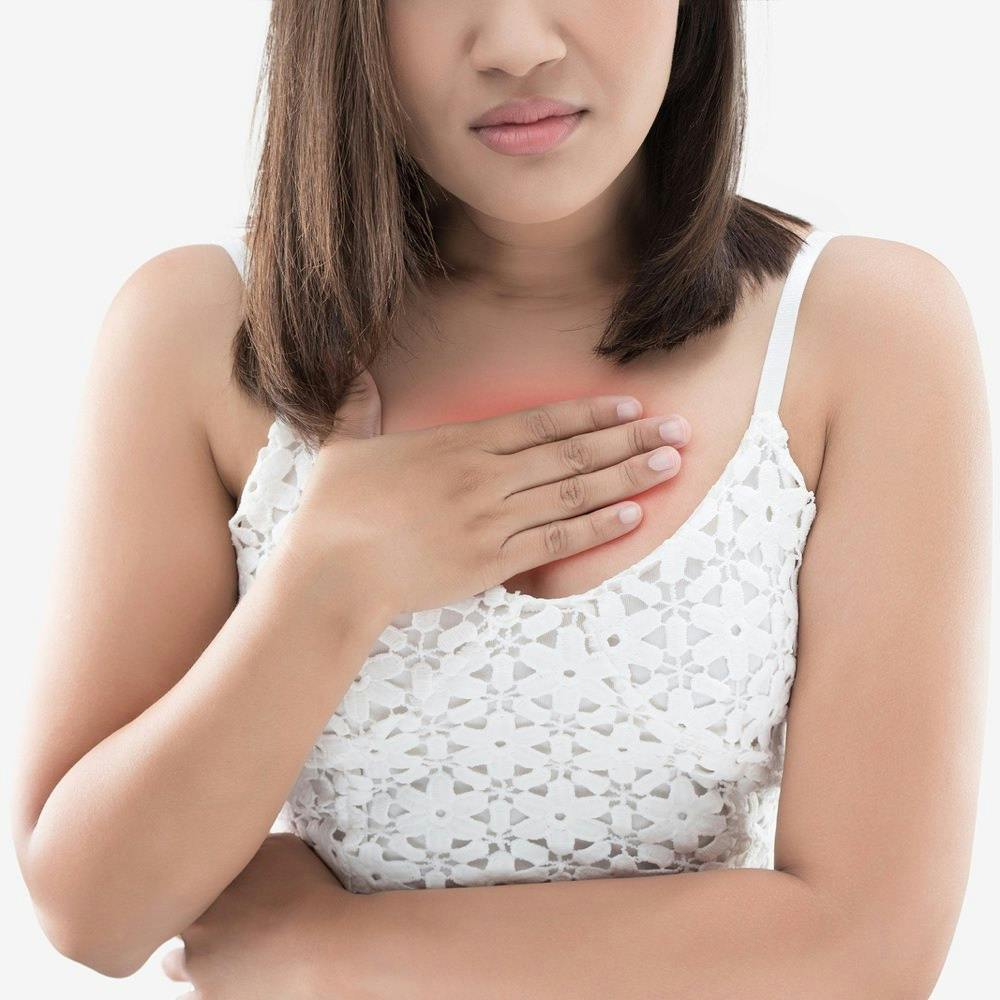 Heartburn is a feeling of burning in people chest, and is a symptom of Acid reflux or GERD. A woman suffering from heartburn on a gray background.
