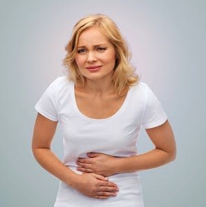 People, healthcare and problem concept &#8211; unhappy woman suffering from stomach ache over gray background
