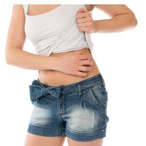 Young woman allergy scratching her abdomen stomach with fingers isolated on a white background
