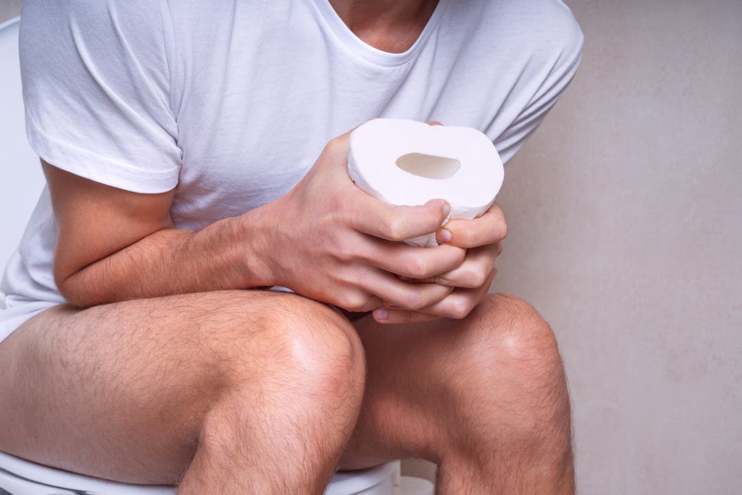 Man sitting on the toilet and suffering from constipation, diarrhea, stomach ache or cramps
