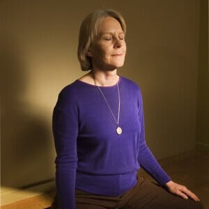 Woman in meditation pose indoors in shadow. ** Note: Slight blurriness, best at smaller sizes
