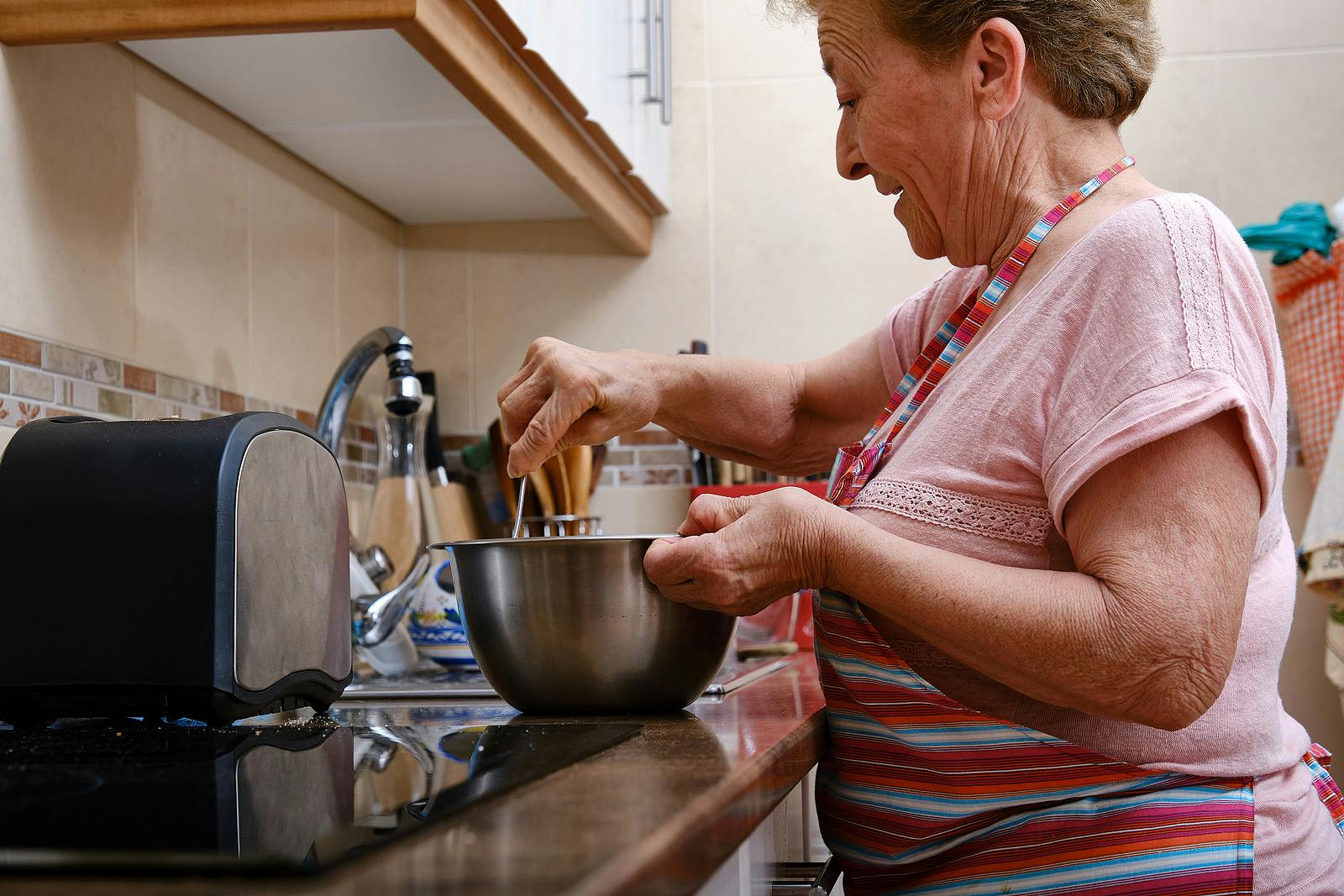 Older woman with arthritis in her hands cooking.
