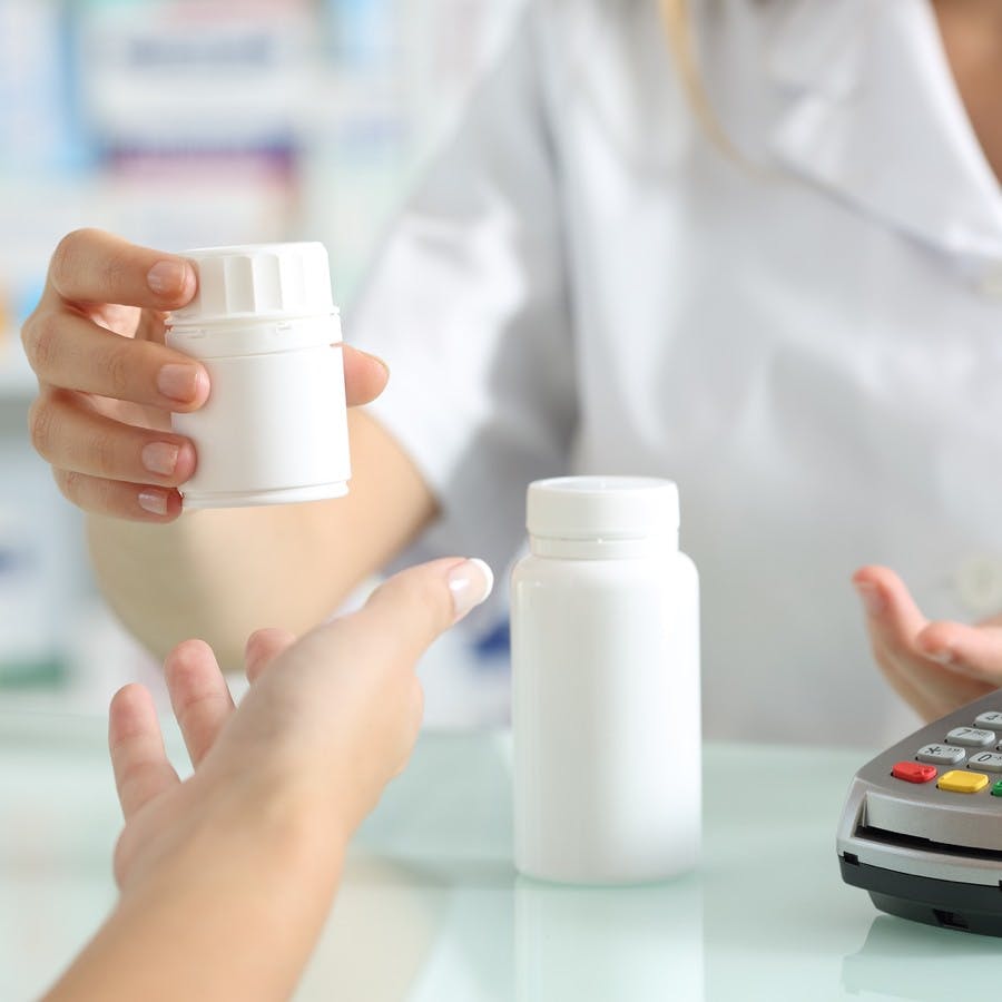 Close up of a pharmacist hands selling medicines to a customer on a pharmacy desk
