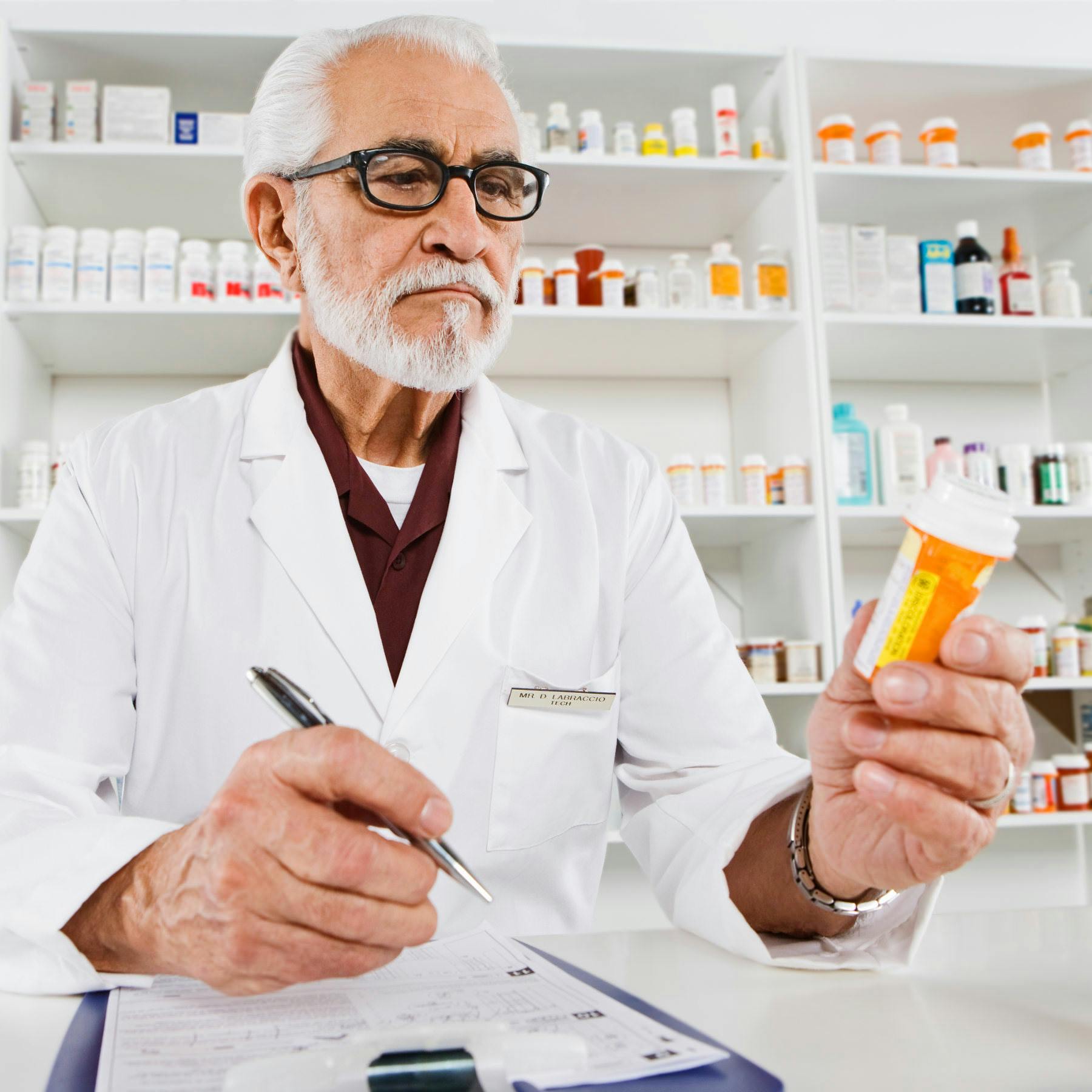 An older local pharmacist reads a pill bottle with a discard date