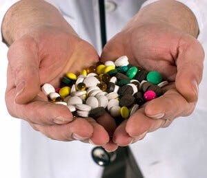 Two hands holding a variety of pill supplements