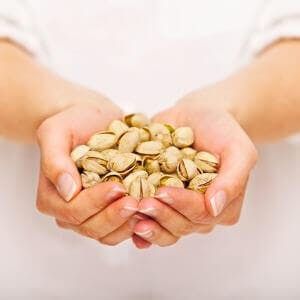 a woman holding a large handful of pistachio nuts