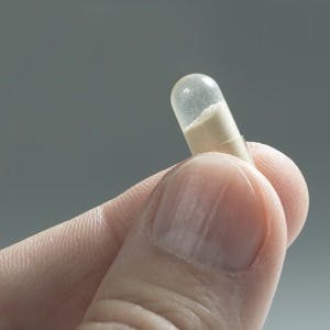 Close up of probiotic capsule between the fingers
