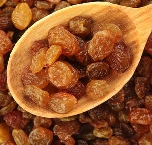 Raisins in wooden spoon on raisins background
