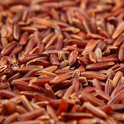 Red rice close-up background. Heap wild brown unpolished rice for vegetarians.
