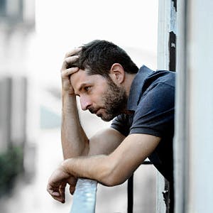 depressed and sad man leaning on a balcony railing
