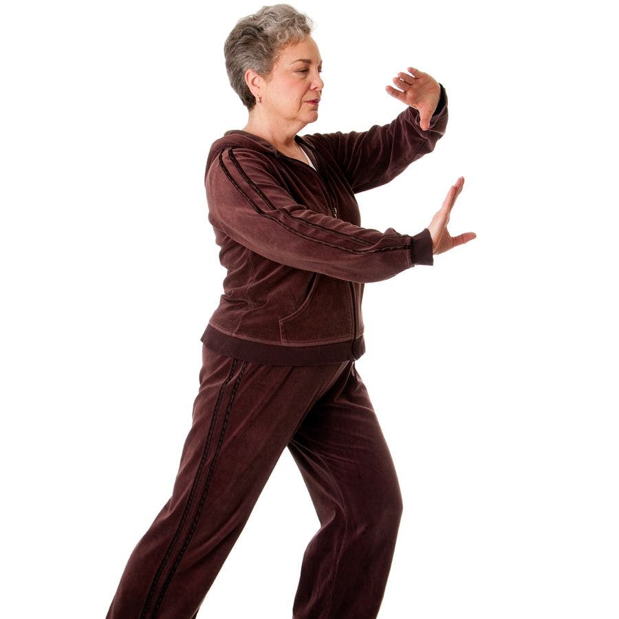 Beautiful Senior woman doing Tai Chi exercise to keep her joints flexible isolated.

